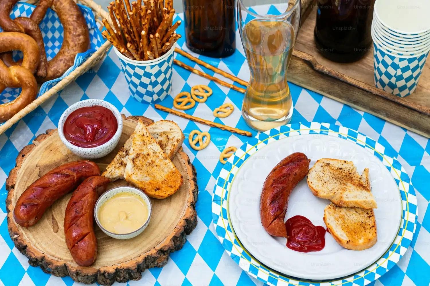 Gegrillte Bratwürste, Brot, Senf und Ketchup auf blau-weiß karierter Tischdecke