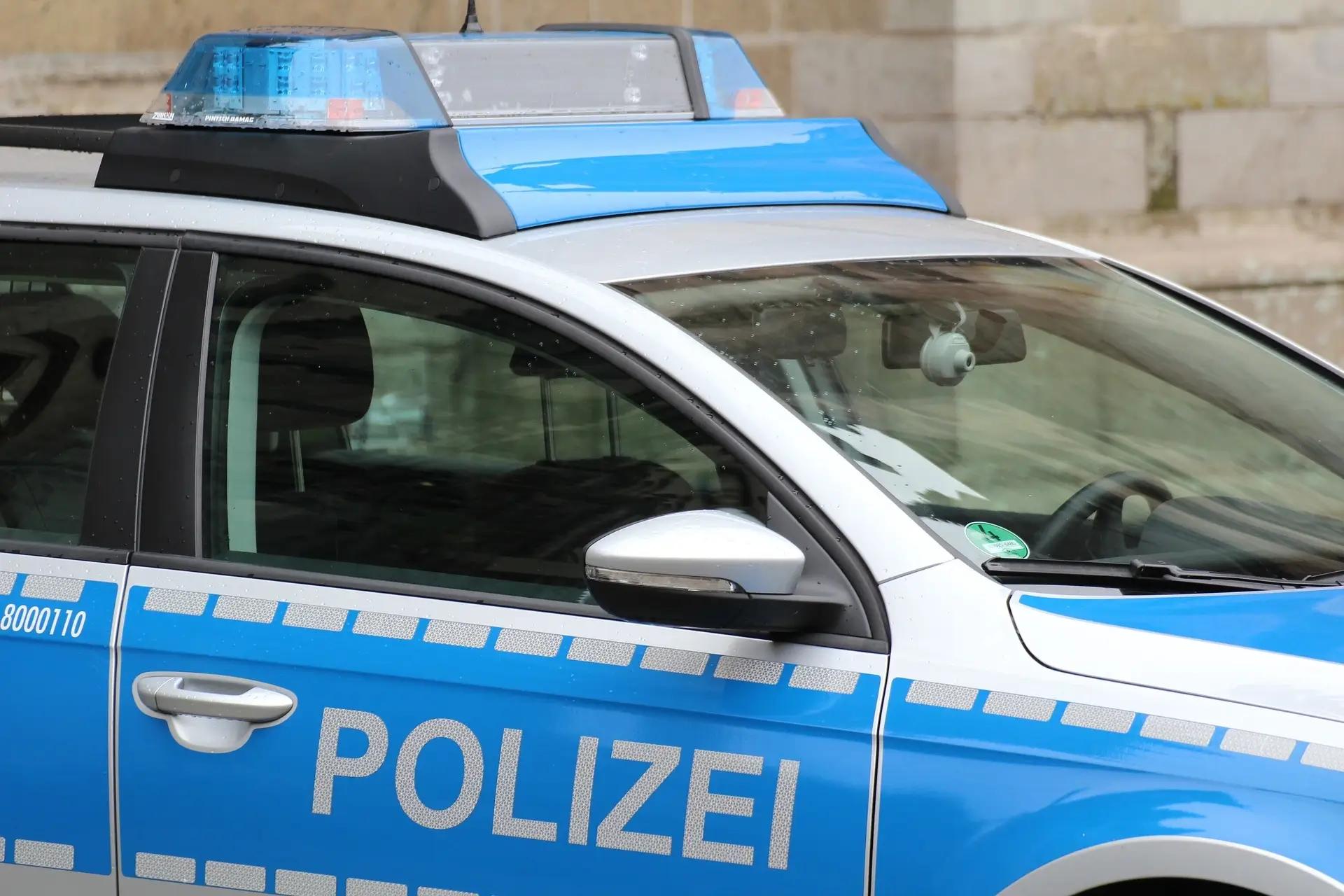 Seitenansicht eines blauen Polizeiwagens mit Schriftzug, Türgriff und Blaulicht