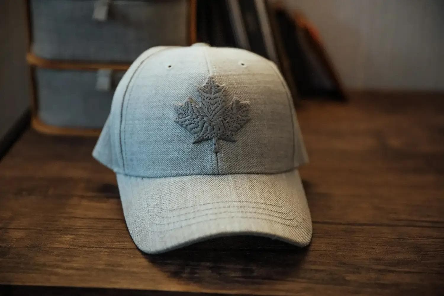 Graues Basecap mit gesticktem Ahornblatt auf Holz