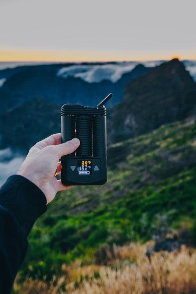Cannabis Vaporizer wird von Hand gehalten, im Hintergrund Natur