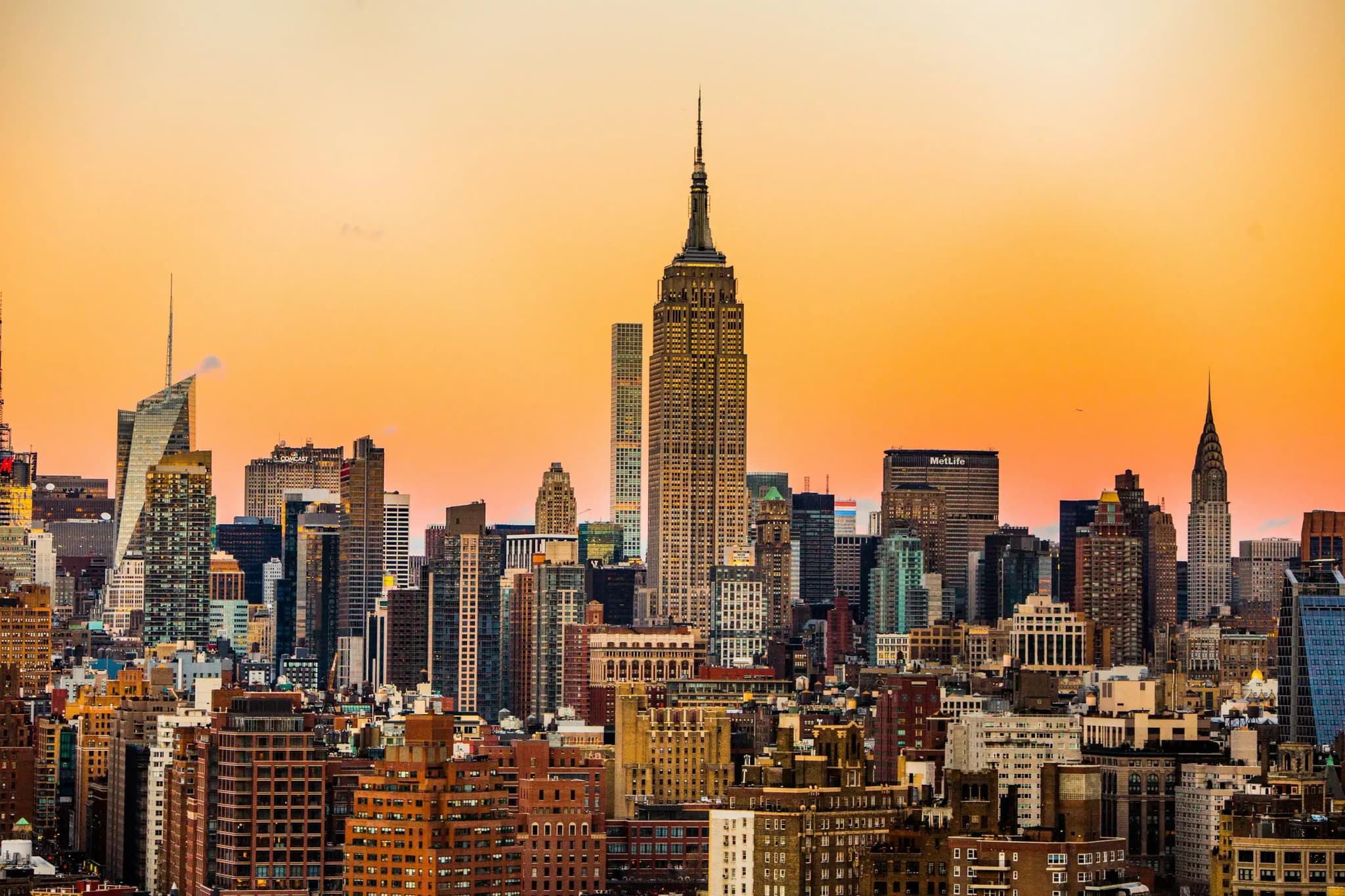 Manhattan-Skyline mit Empire State Building vor orangefarbenem Abendhimmel